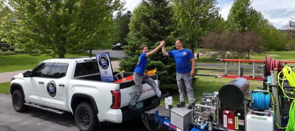 Two men are giving each other a high five in front of a truck.