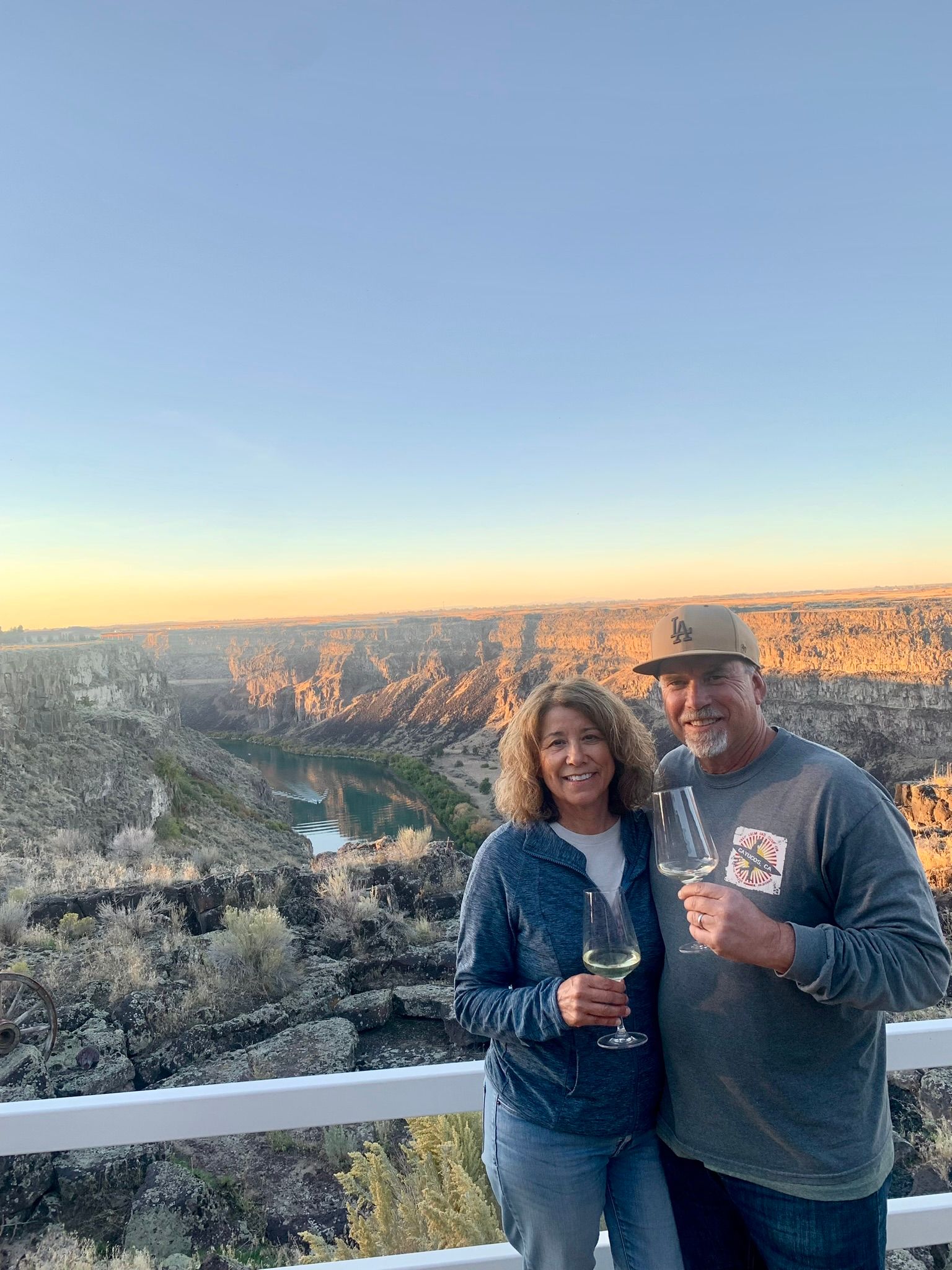 A man and a woman are standing next to each other on a balcony holding wine glasses.