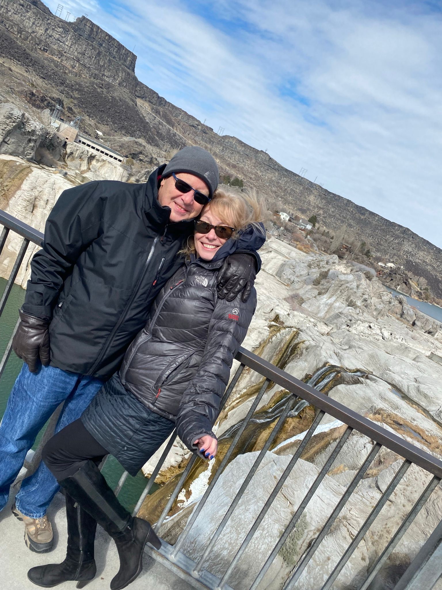 A man and a woman are standing next to each other on a bridge.