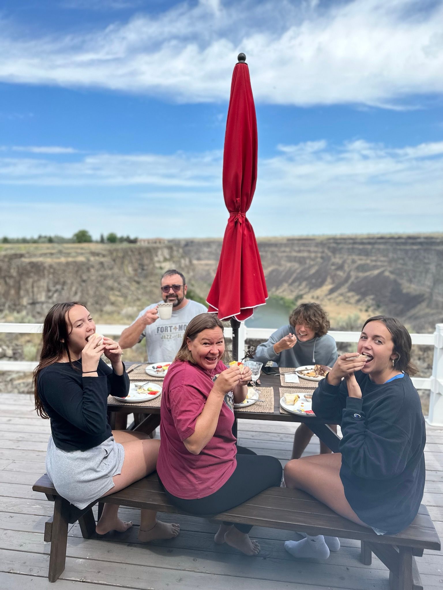 A group of people are sitting at a picnic table eating food.
