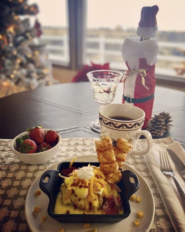 Holiday breakfast spread with strawberries, pastries, coffee, and a decorated bottle on a festive table