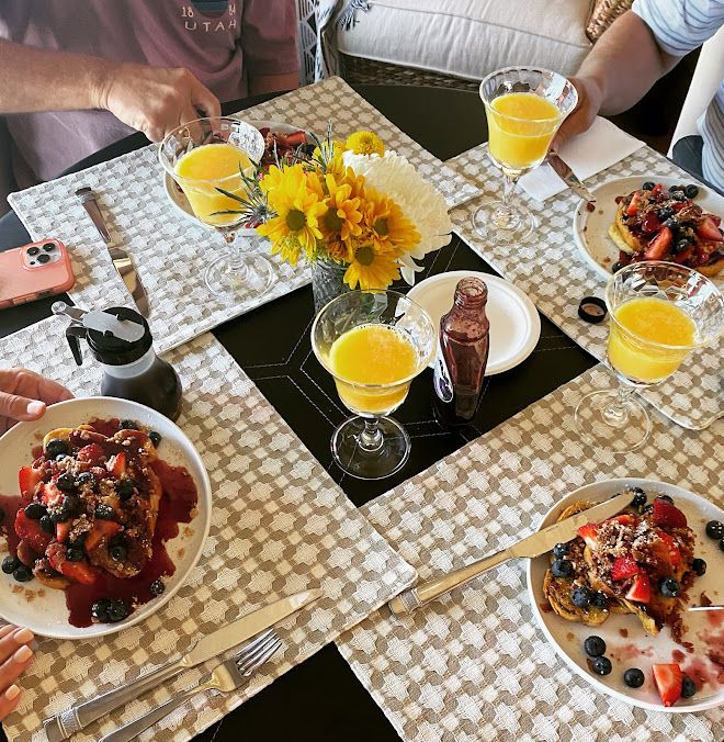 Breakfast table with fruit, pastries, orange juice, and a yellow flower centerpiece