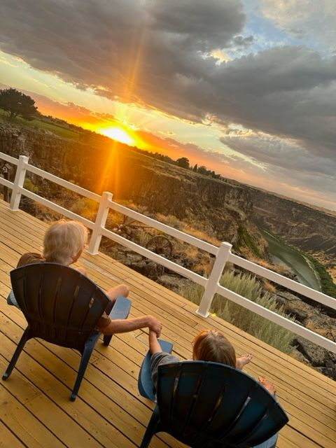 Two children on deck watching sunset over canyon.