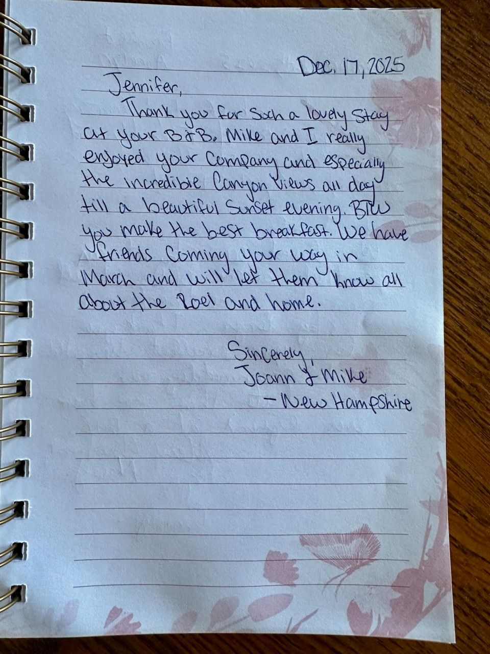 Handwritten note on lined spiral notebook page with floral border and pink stain at bottom