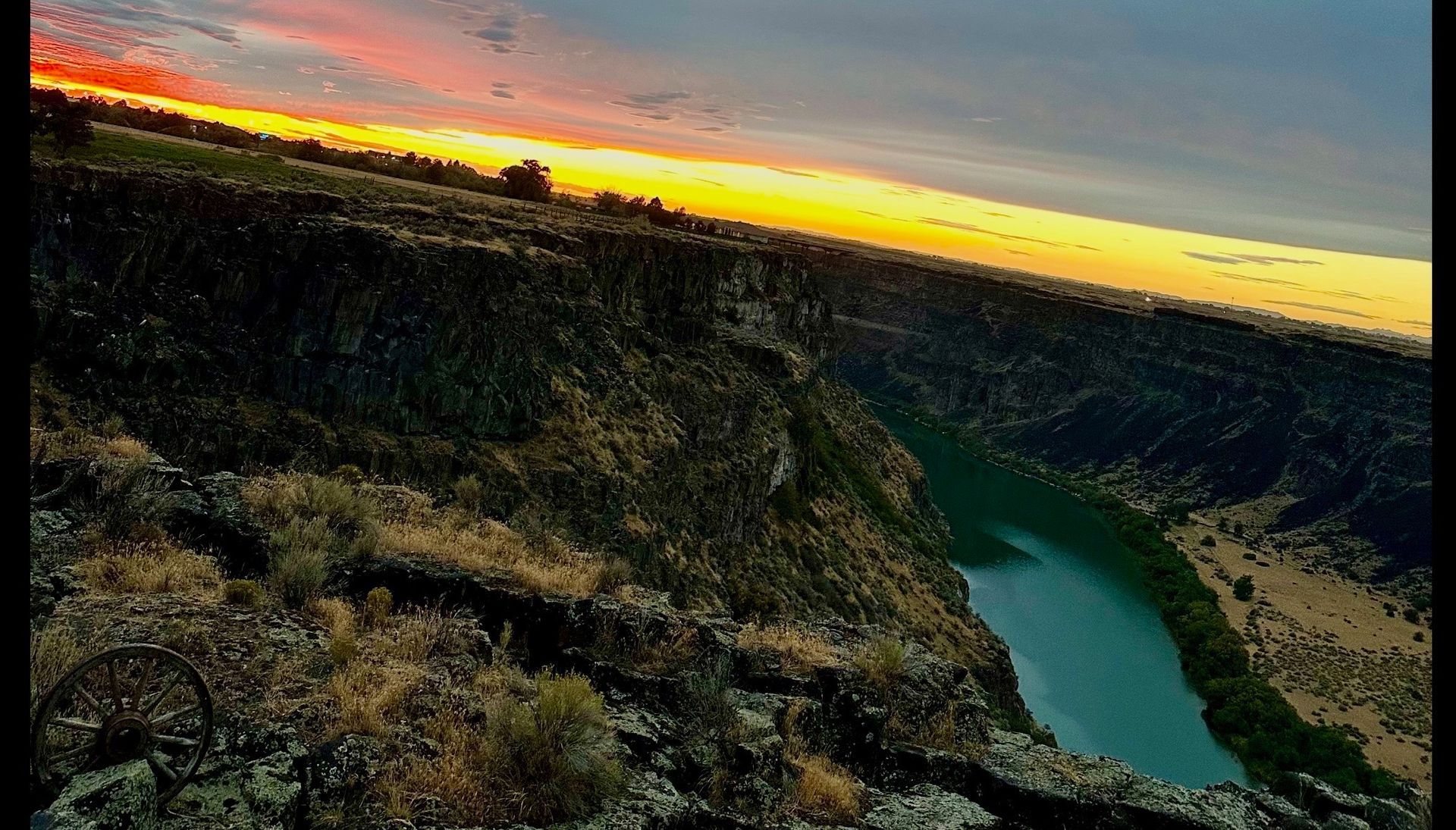 Sunset over a rugged canyon with a winding turquoise river below
