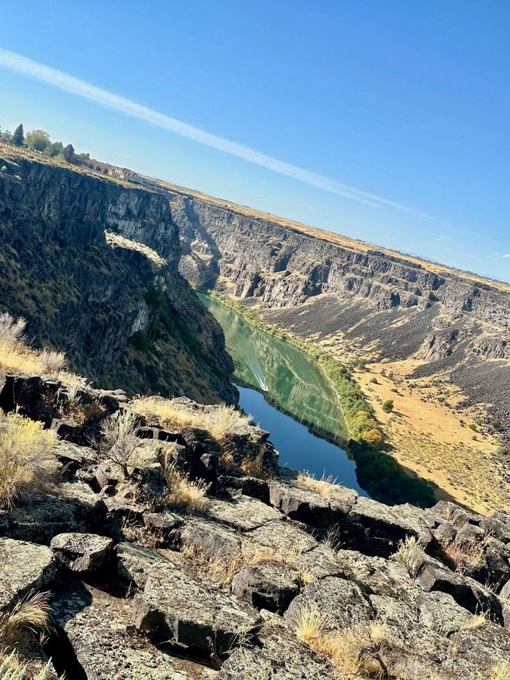 Steep canyon with a winding river and rocky foreground under a clear blue sky