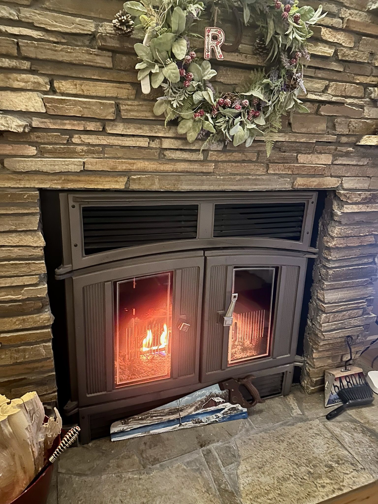 Fireplace with lit fire, brown brick surround, and a festive wreath.