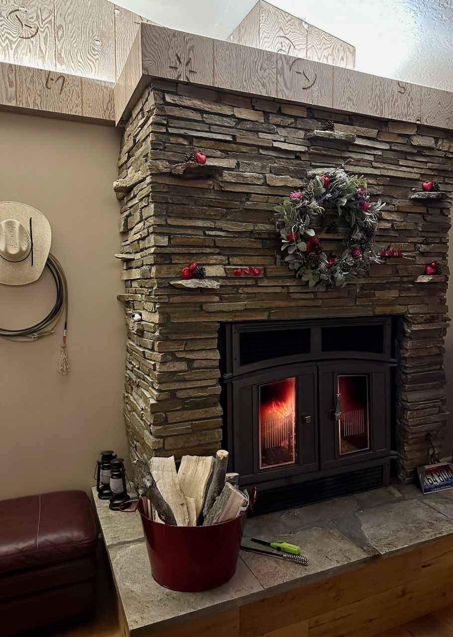 A living room with a fireplace and a cowboy hat on the wall.
