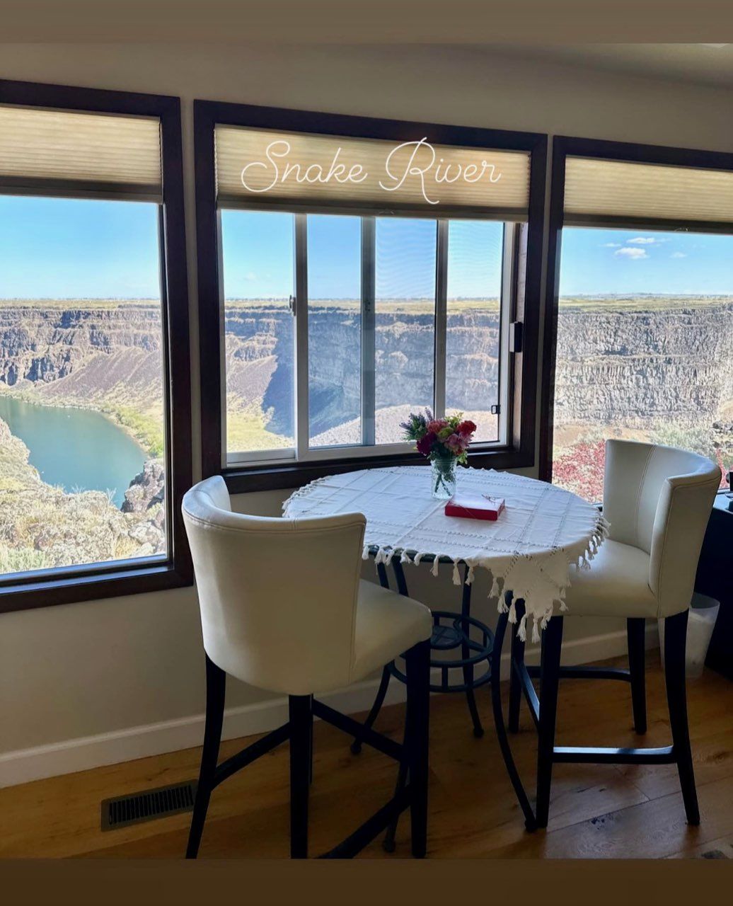 A room with a table and chairs and a window that says snake river