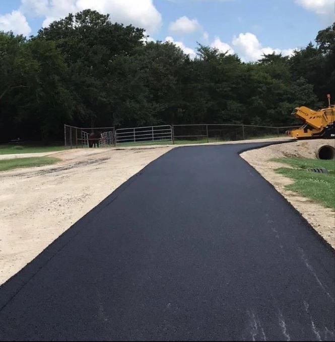 A black road with a yellow bulldozer in the background