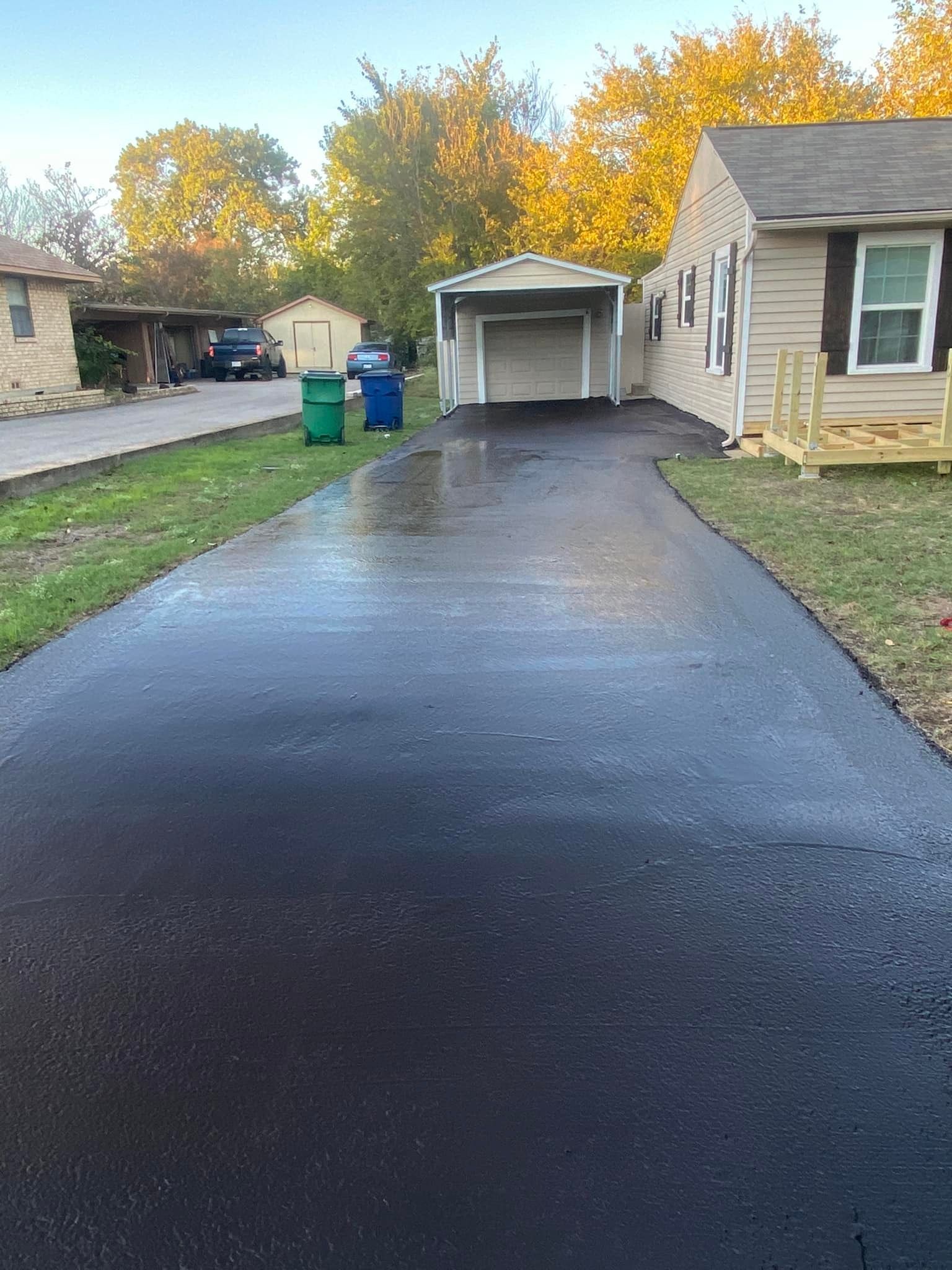 A black driveway leading to a house with a garage.