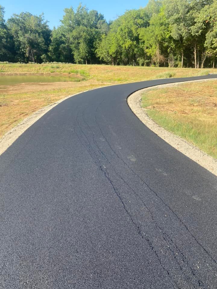 A curvy road going through a field with trees on the side.