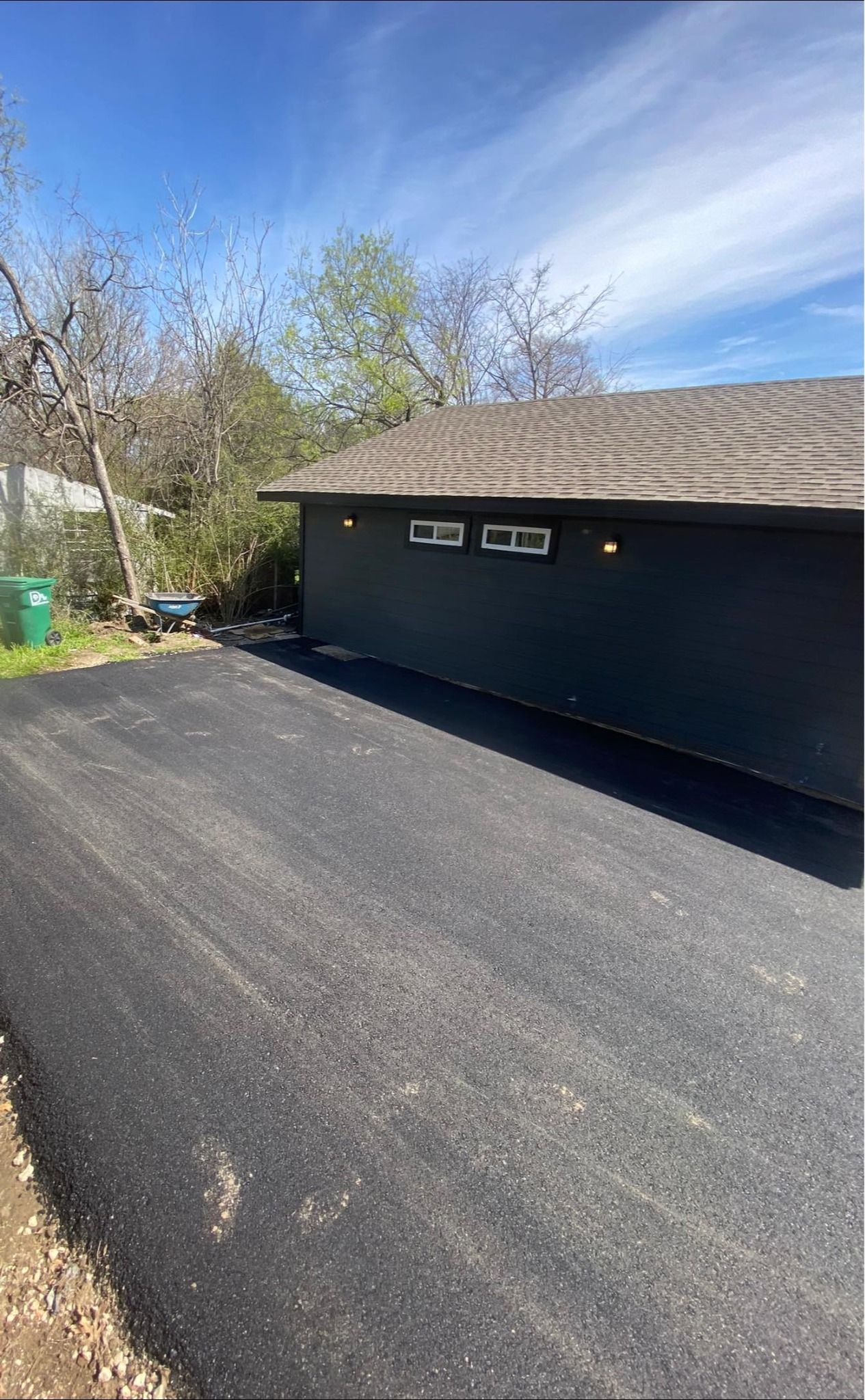 A black garage door is parked in a driveway next to a house.