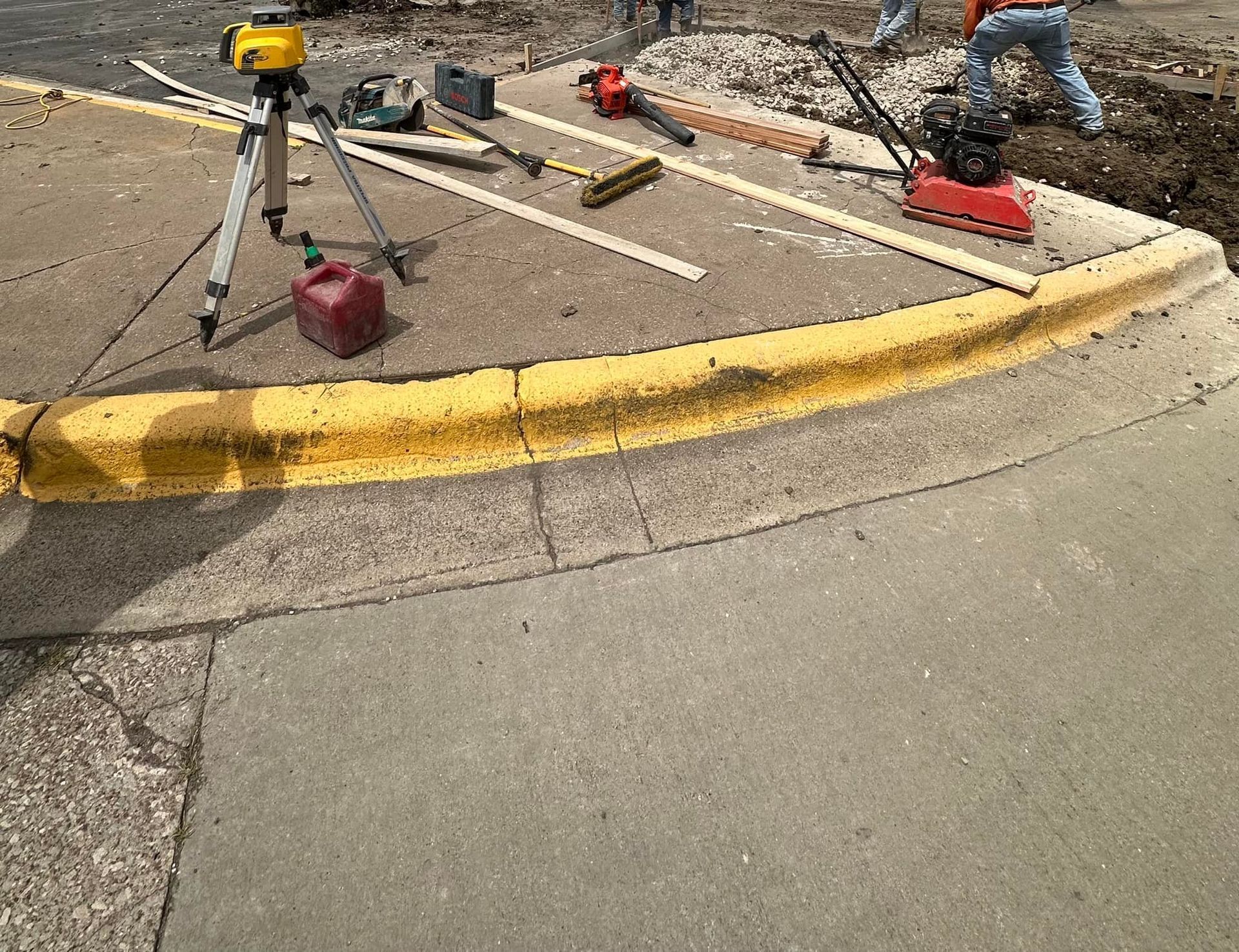 A tripod is sitting on the sidewalk next to a yellow curb.