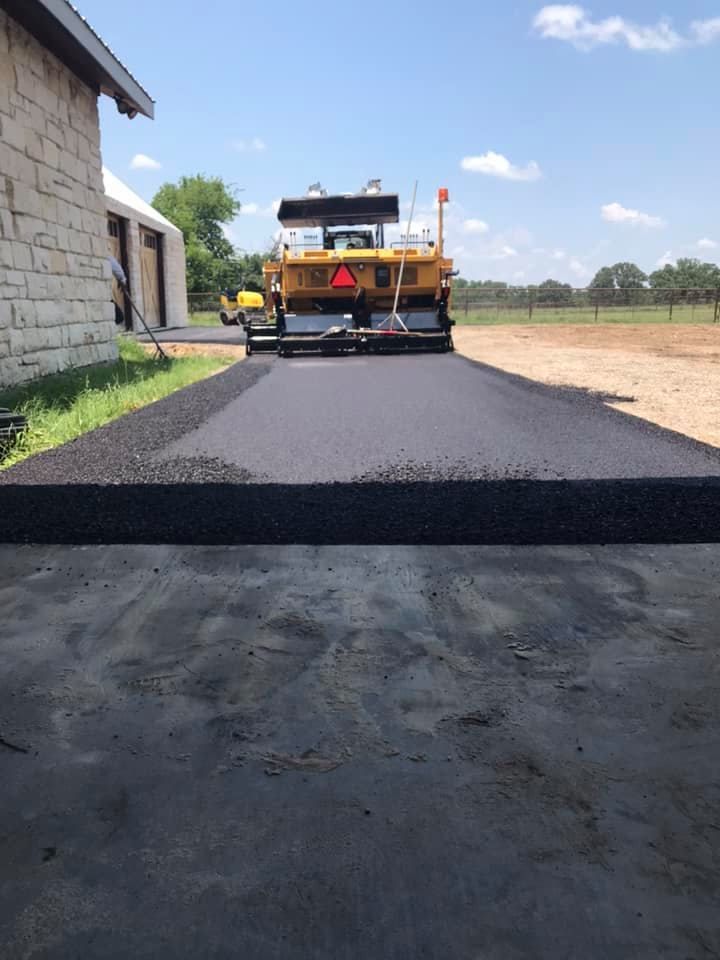 A yellow truck is driving down a road next to a building