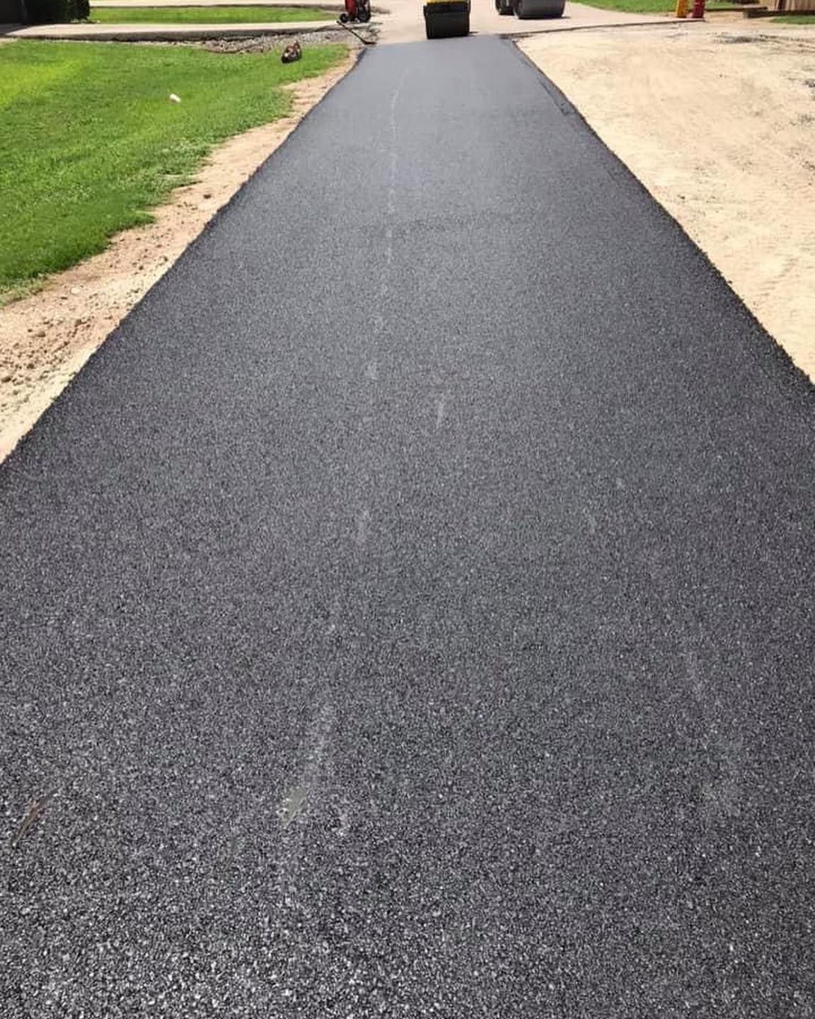 A black asphalt road going through a grassy area.