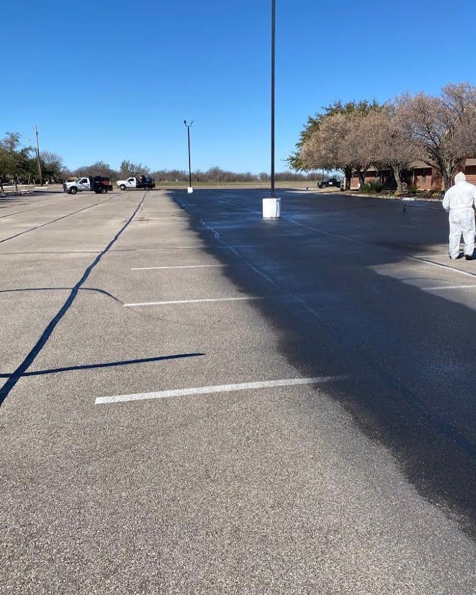A person is walking through a parking lot on a sunny day