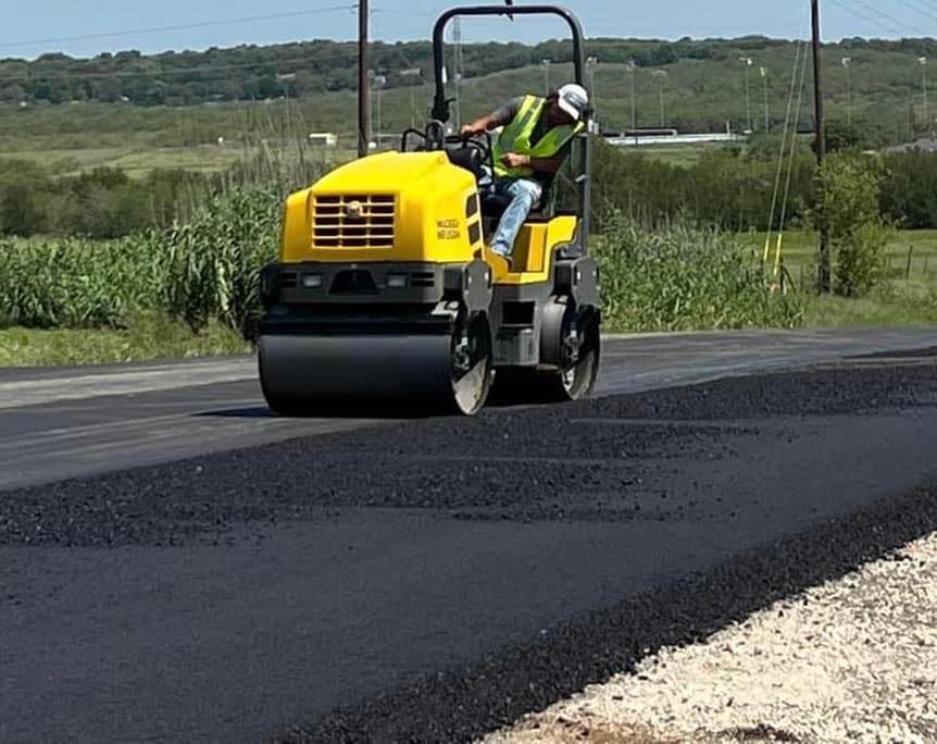 A man is driving a yellow roller on a road
