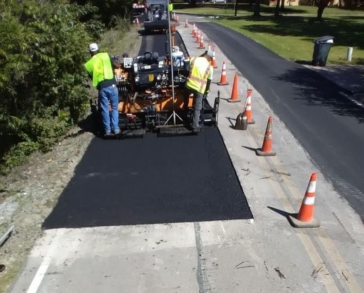 A group of construction workers are working on a road