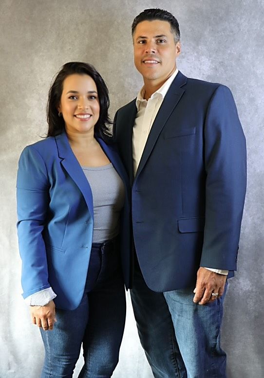 Woman and man posing together, both in business casual attire. real estate team