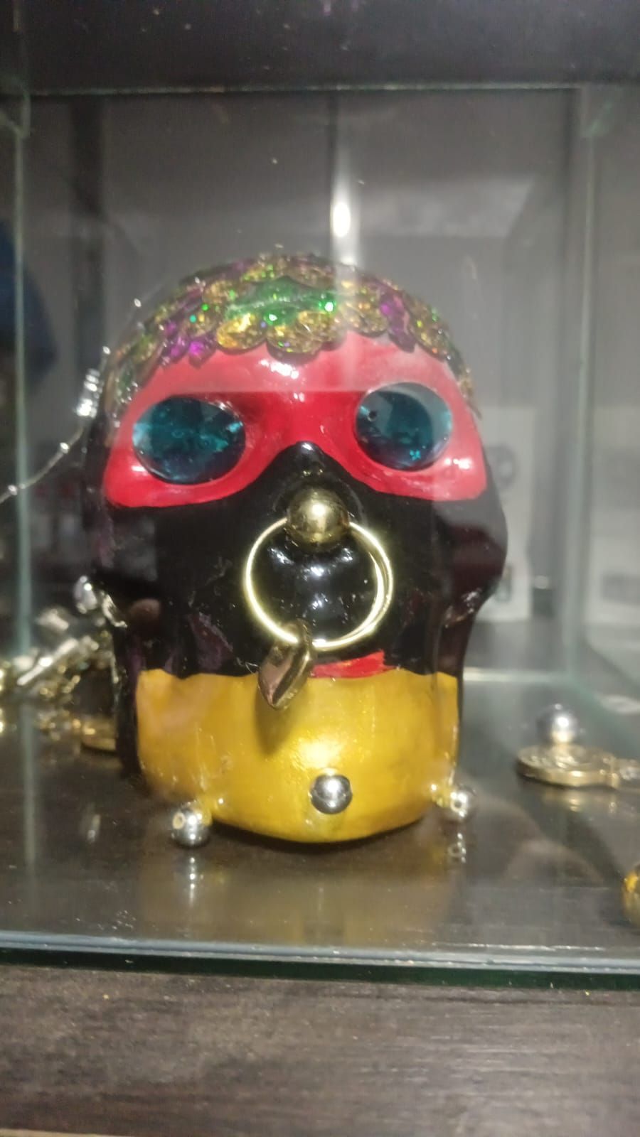 Cráneo decorado con pintura roja, negra y dorada, un gran anillo en la nariz y adornos de joyas.