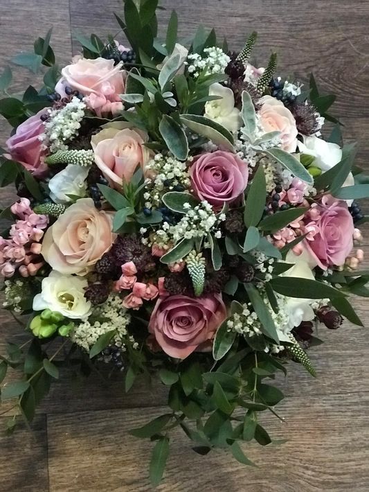 Bouquet of red roses with green eucalyptus leaves wrapped in red and brown paper.
