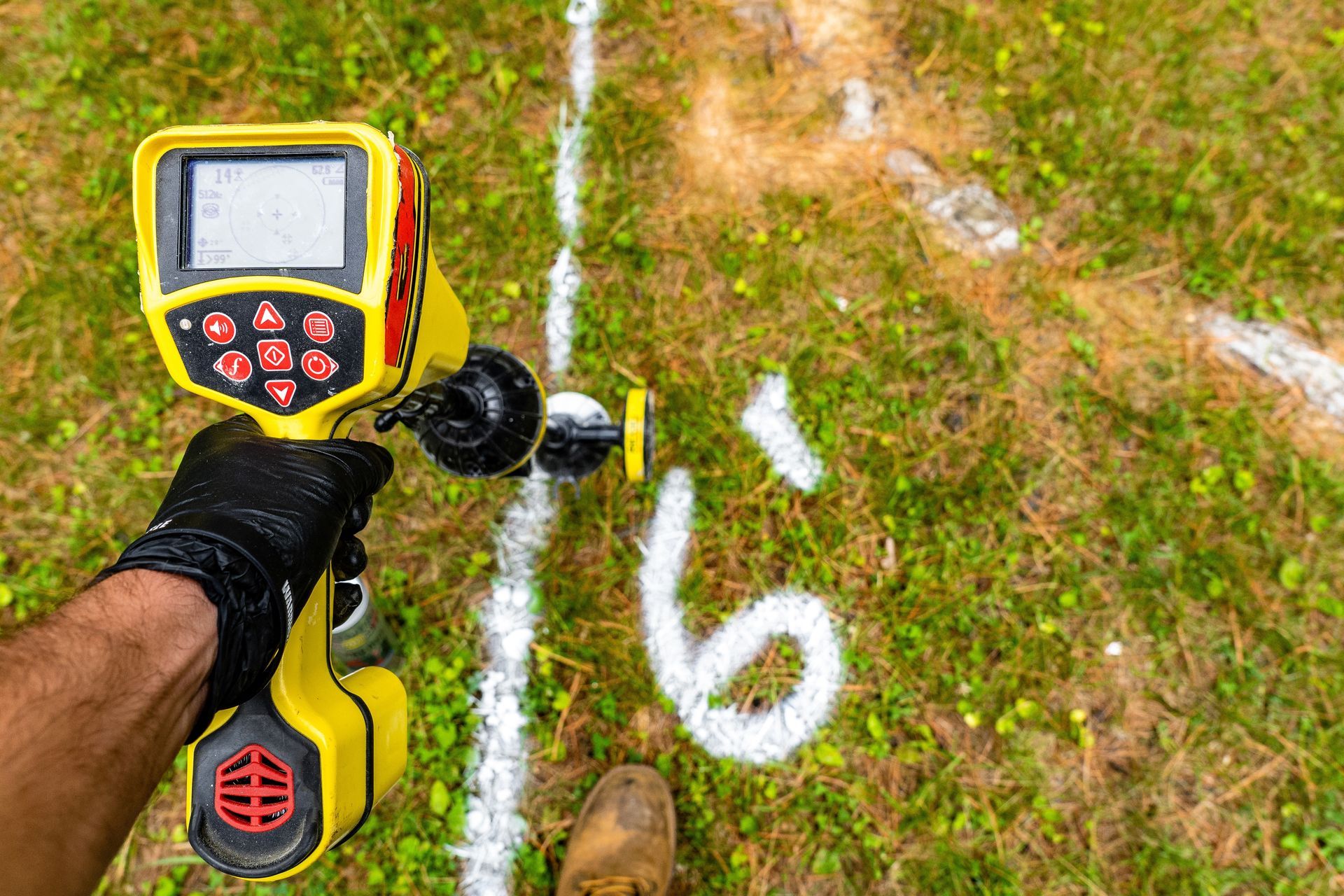 A person is using a detector to find a hole in the ground.