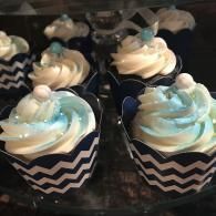 Blue and white frosted cupcakes in black-and-white chevron wrappers arranged on a tray