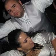 Two people reclining closely together in white clothing in a dimly lit setting.