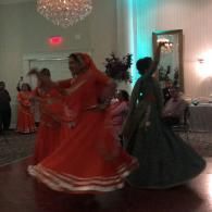 Two dancers in flowing red and dark green dresses spinning in a banquet hall