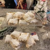 Dessert tray with powdered sugar pastries on a tiered stand at a table, with flowers beside it