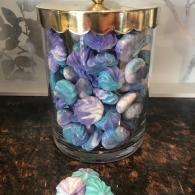 Clear jar filled with blue, purple, and white wrapped candies on a dark countertop