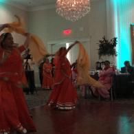 Dancers in red costumes perform with flowing scarves in a decorated banquet hall