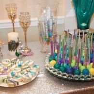 Decorated dessert table with colorful cake pops, frosted cookies, and glass candle holders