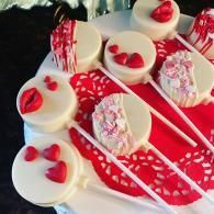 White chocolate berry cake pops with red sprinkles on a red tray