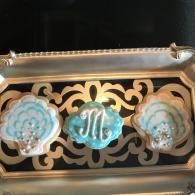 Three blue glass ornaments on an ornate gold tray with scrollwork.