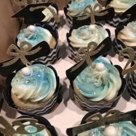Blue and white swirled cupcakes with black wrappers and silver ribbon toppers on a tray