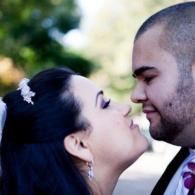 Two people leaning in for a kiss outdoors, with a soft green blurred background.