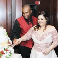Couple in formal attire cutting a decorated cake at a celebration