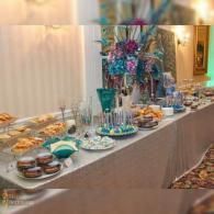 Buffet table with desserts, drinks, and a tall floral centerpiece at a banquet event