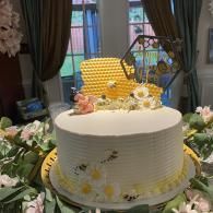 White floral cake with yellow topper on a decorated table indoors