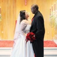 Bride in white gown and groom in black suit standing close together at a wedding ceremony