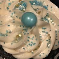 White frosted cupcake with blue sprinkles and a blue candy topper