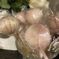 Pastel pink and beige wrapped candy lollipops tied with ribbons in a decorative container