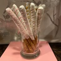 Pastel-striped wafer cookies in a glass jar on a pink surface