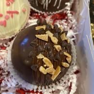 Chocolate truffle topped with almond flakes in a red-and-white bakery box