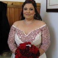 Woman in a white and red off-shoulder dress holding a bouquet of red roses indoors