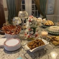 Holiday buffet spread on a granite table with appetizers, plates, candles, and festive decorations
