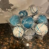Wrapped blue and white spherical decorations clustered in a clear container on a countertop
