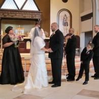 Wedding ceremony in a church, with the bride and groom exchanging vows beside an officiant.